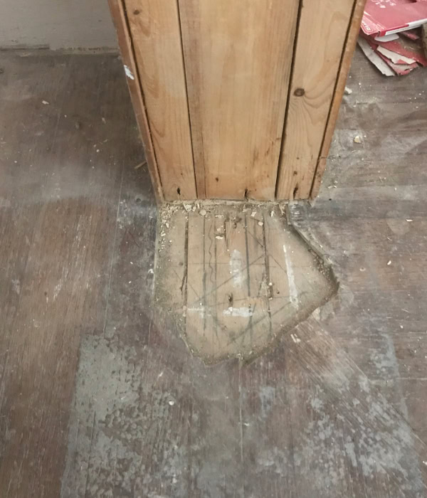 Downstairs newel post with missing patch of flooring in front of it, indicating that the original newel post had been removed