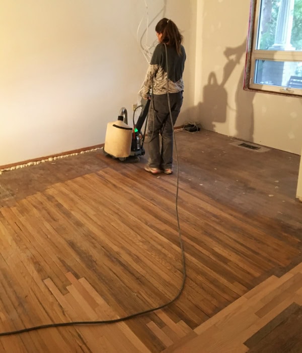 Alanna using the large stand-up drum sander to refinish the downstairs flooring