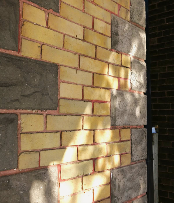 Yellow brick exterior wall with flecks of daylight shining on it
