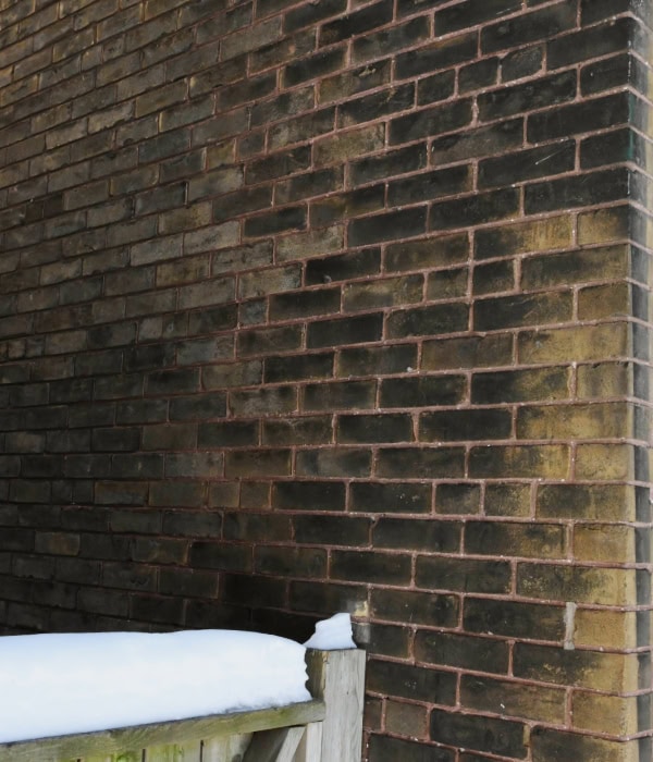 Exterior wall made of solid brick. If you look closely, you can see that some of the bricks are turned inward and you can see the short end of the brick every 6 rows. This was done to tie the wythes of brick together.