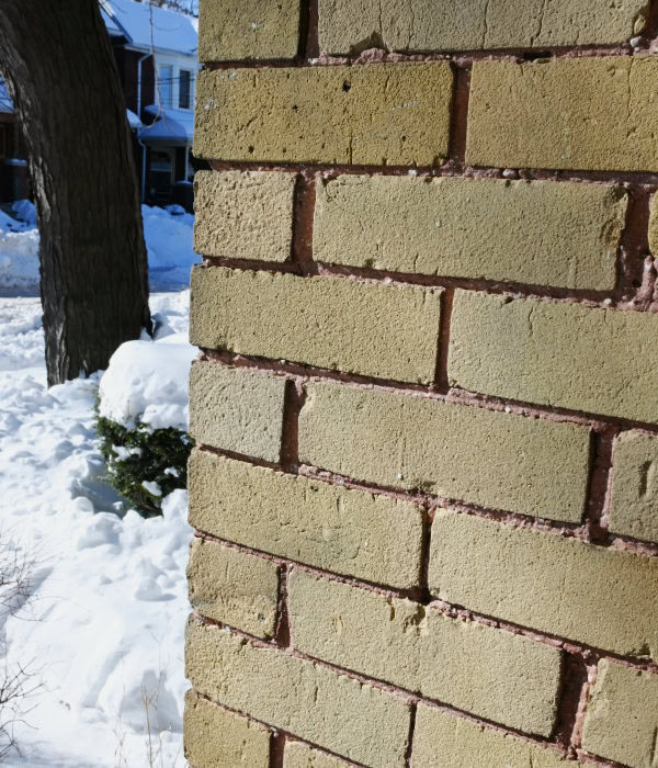 Up close image of solid yellow brick exterior wall of an old home.